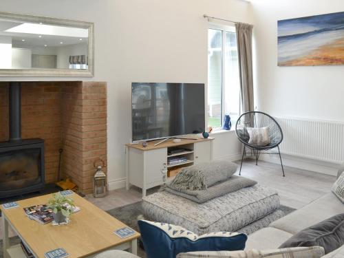 ein Wohnzimmer mit Sofa und Fernseher in der Unterkunft Dune View in Beadnell