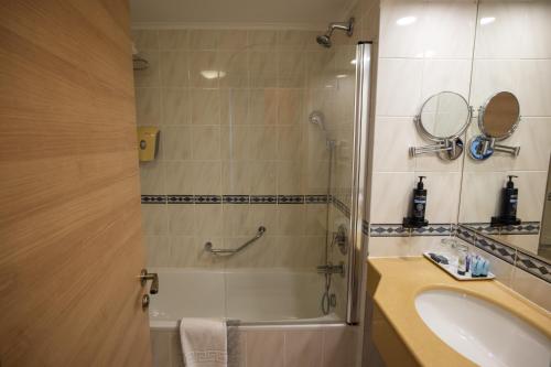 a bathroom with a tub and a sink and a shower at Grand Beach Hotel in Tel Aviv