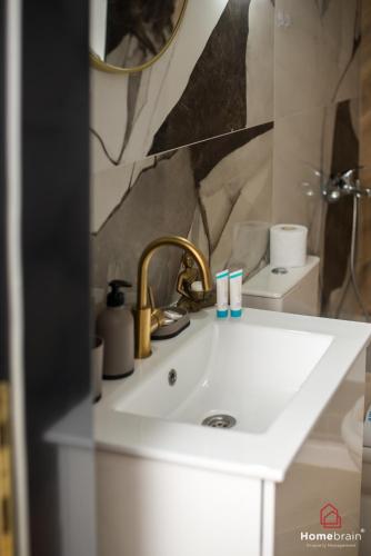 a white bathroom sink with a gold faucet at Kleoniki's Boutique apartment By Homebrain in Alexandroupoli