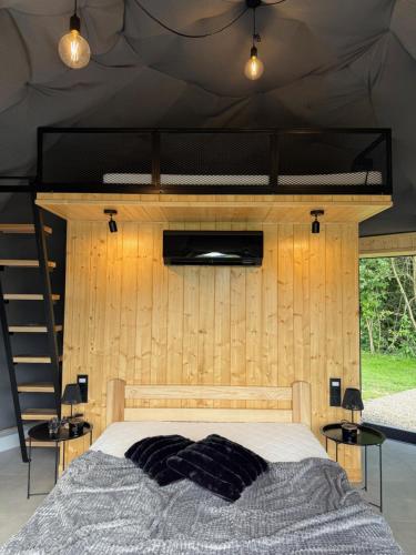 a bed in a room with a wooden wall at Tatra Glam Krynica Zdrój - Sieć noclegowa Tatra Glamp in Czyrna
