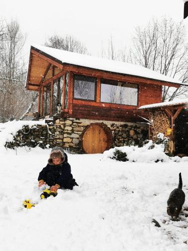 a child sitting in the snow in front of a cabin at Studio Belvedere in Mălăeşti