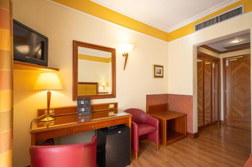 a hotel room with a desk and a mirror at Hotel Il Chiostro by LVG Hotel Collection in Verbania