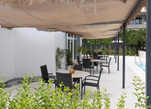an outdoor patio with tables and chairs under a roof at Hotel Sea Sand in Sveti Vlas