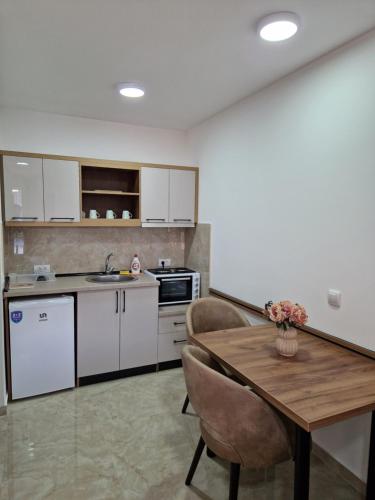 a kitchen with white cabinets and a wooden table at Apartmani Nataly M2 in Veliko Gradište