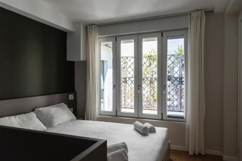 une chambre avec un lit et une grande fenêtre dans l'établissement Youhosty - Zanella 68, à Milan