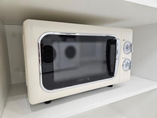 a white microwave oven sitting on a shelf at The Stay 150 Anyang in Anyang