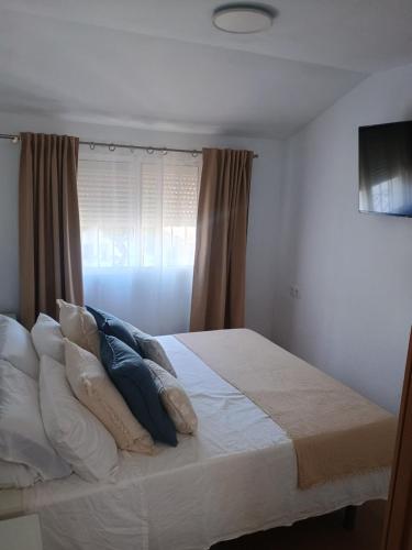 a bedroom with a white bed with pillows and a window at Centro Kennedy in Algeciras