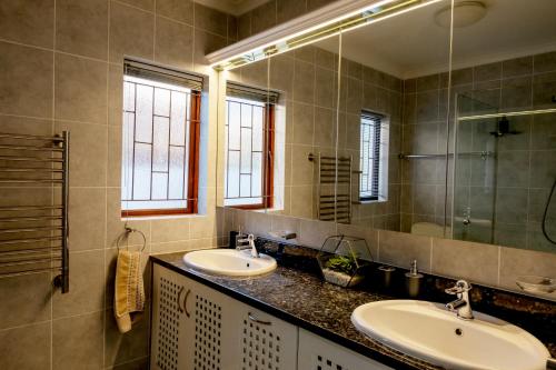 a bathroom with two sinks and a large mirror at Fluke Tide - Stylish Knysna Home with Pool & Views in Knysna