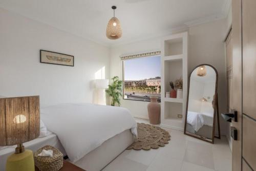 a white bedroom with a large bed and a mirror at Fancy Pyramids View Khan Giza's Gem in Cairo