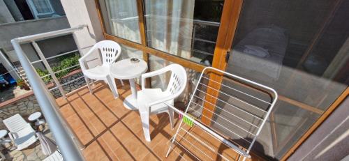 two white chairs and a table on a balcony at Family hotel Favourite in Obzor