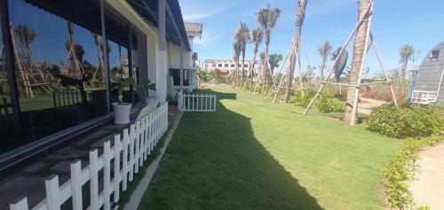 a porch of a house with green grass and palm trees at Happy Garden Hồ Tràm in Ho Tram