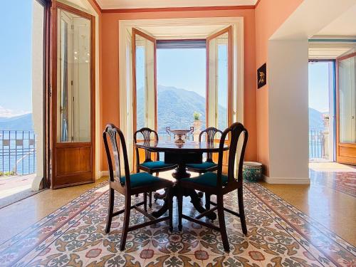 a dining room with a table and chairs and windows at Villa Celeste Argegno - Lake Como in Argegno