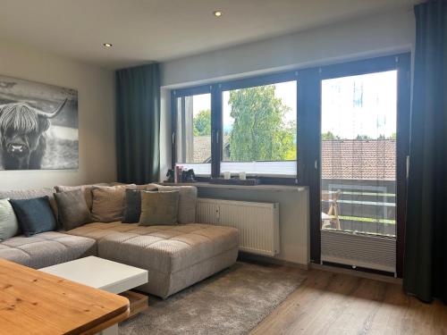 a living room with a couch and a large window at ChiemNest Fewo in Grabenstätt