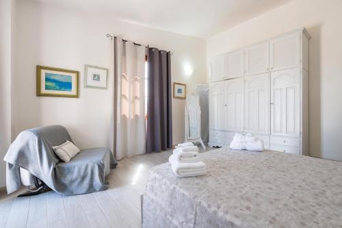 a white bedroom with a bed and a chair at Villa D'Oro in La Maddalena