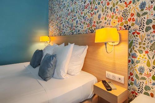 a hotel room with a bed and a yellow lamp at Hôtel Du Centre, un hôtel AMMI in Nice
