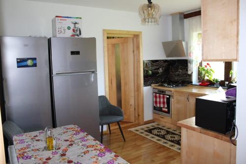 a kitchen with a stainless steel refrigerator and a table at Casa la grig in Râşnov
