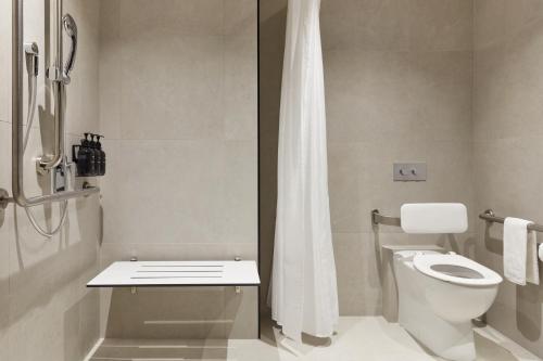 a white bathroom with a toilet and a shower at Hotel Indigo Auckland by IHG in Auckland