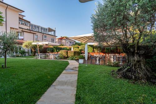 un árbol en medio de un césped con un edificio en Hotel Luna, en Marina di Massa