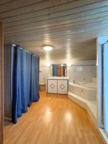 une grande salle de bain avec des rideaux bleus et une baignoire dans l'établissement APPARTEMENT MOUFLONS, à La Llagonne
