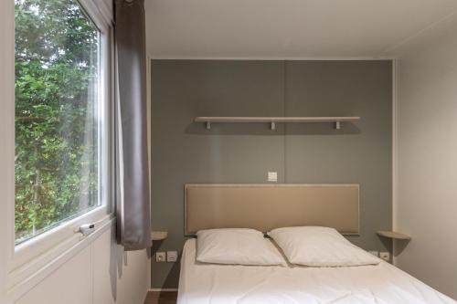 a bed in a room with a large window at Les Rives d’Auzon Mobil-home 6 pers in Lavilledieu