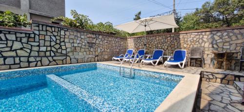 a swimming pool with blue chairs and an umbrella at Family hotel Favourite in Obzor