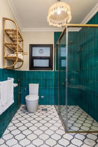 a green tiled bathroom with a toilet and a chandelier at Fancy Pyramids View Khan Giza's Gem in Cairo