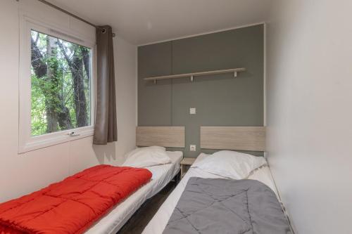 two beds in a room with a window at Les Rives d’Auzon Mobil-home 6 pers in Lavilledieu