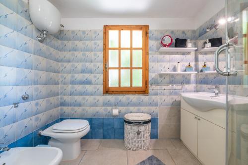 a blue tiled bathroom with a toilet and a sink at Villa D'Oro in La Maddalena