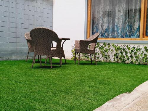 three chairs sitting on a porch with green grass at Hearth and Haven Homestay in Leh