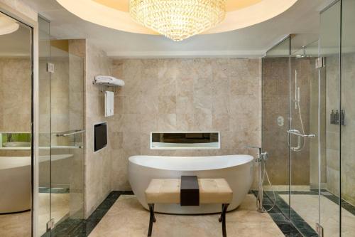a bathroom with a bath tub and a chandelier at Sheraton Bandung Hotel & Towers in Bandung