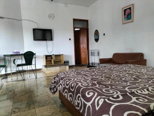 a bedroom with a bed and a flat screen tv at Nur Alam Hotel Lembang in Lembang
