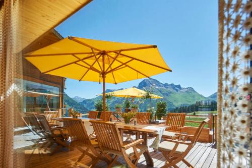 stół i krzesła z żółtym parasolem na tarasie w obiekcie Hotel Mohnenfluh w Lech am Arlberg