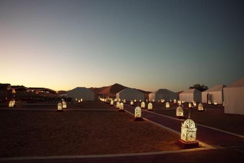 a group of lit candles in a field with tents at Safari luxury camp in Merzouga