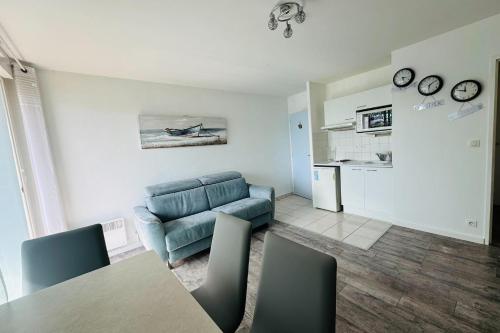 un salon avec un canapé bleu et une table dans l'établissement Beautiful studio with terrace - harbour view, à Ouistreham