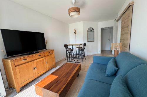 un salon avec un canapé bleu et une télévision à écran plat dans l'établissement T2 well equipped with balcony in Caen, à Caen