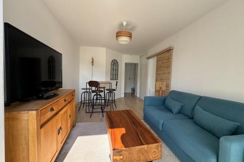 un salon avec un canapé bleu et une télévision dans l'établissement T2 well equipped with balcony in Caen, à Caen