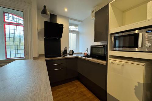 une cuisine avec des armoires noires et un four micro-ondes dans l'établissement Charming apartment in the center of Caen, à Caen