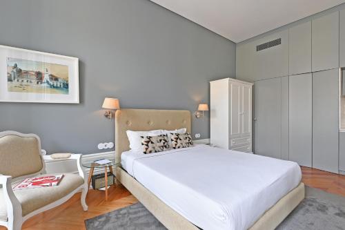 a bedroom with a large white bed and a chair at Villa Mouzinho by ON Apartments in Porto