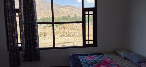 a bedroom with a window with a view of a mountain at Mountain palace kargil in Kargil