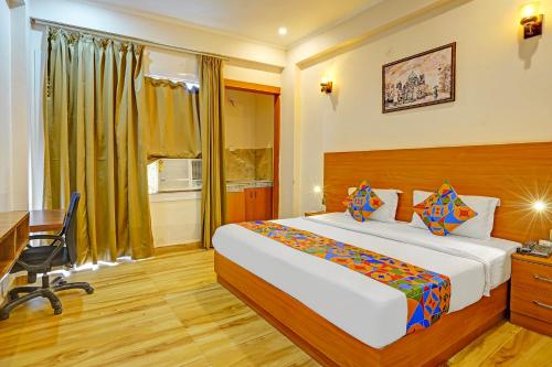 a hotel room with a bed and a desk and a window at FabHotel The Viraaj in Noida