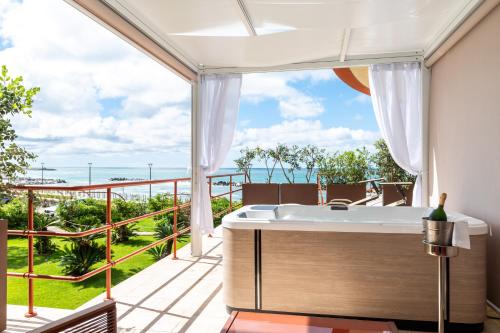 a bathroom with a tub and a balcony with a view at Grand Hotel Torre Fara in Chiavari