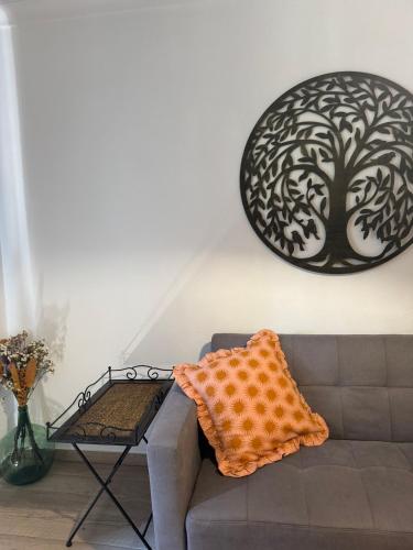 a couch in a living room with a tree picture on the wall at Casa das Laranjeiras in Alfarim