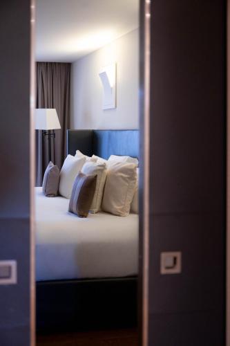 a bedroom with a bed with white pillows at L'Hôtel & Spa du Castellet in Le Castellet