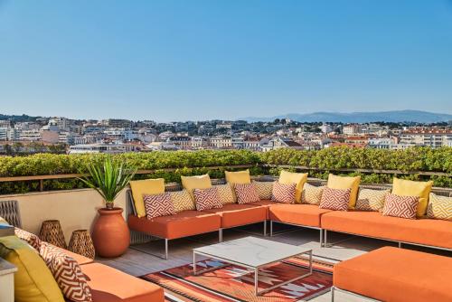 a balcony with orange and yellow furniture and a city at Hôtel Barrière Le Gray d'Albion in Cannes