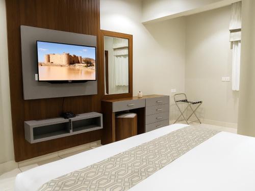 a bedroom with a bed and a tv on a wall at Al Alamein Suites in Tabuk