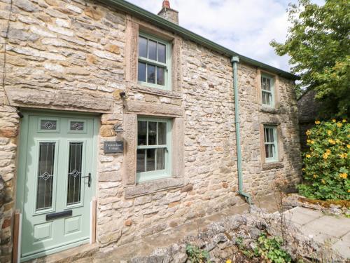 a stone house with a green door and windows at Trickett Gate Cottage in Castleton
