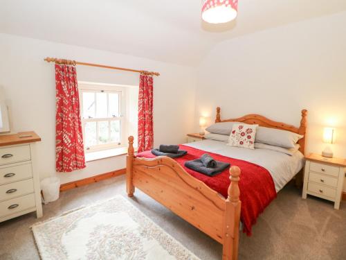 1 dormitorio con cama de madera y ventana en Trickett Gate Cottage, en Castleton