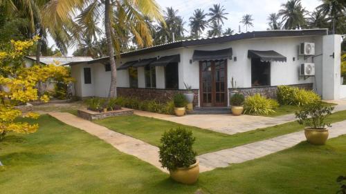 a white house with trees and plants in a yard at Kadolana Hotel and Restaurant in Puttalam
