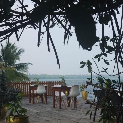 a table and chairs on a patio overlooking the water at Kadolana Hotel and Restaurant in Puttalam