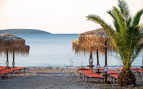 a beach with chairs and straw umbrellas and the ocean at The Grove Seaside Hotel in Dhrepanon